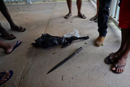 Los indígenas de Waimiri-Atroari parados alrededor de un cuchillo que, según dicen, fue utilizado por los militares en la década de 1970 para matar a muchos de sus familiares en la reserva