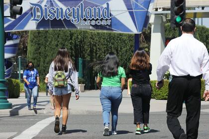 Los invitados caminan en su camino para ingresar al Distrito Downtown Disney el primer día que reabrió tras el cierre temporal debido a la pandemia COVID-19