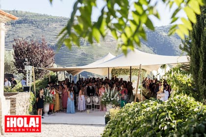 Los invitados esperan la llegada de los novios protegidos del sol. Al fondo, puede verse el altar con un gran arco de flores blancas donde se celebró la boda. 