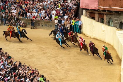 Los jinetes cabalgan a toda velocidad alrededor de la plaza y el equipo vencedor recibe como premio el estandarte que realizó un artista para cada ceremonia. Gentileza del Consorzio per la Tutela del Palio di Siena.
