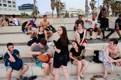 Los jóvenes se reúnen en la ciudad costera israelí de Tel Aviv el 19 de abril de 2021, después de que las autoridades anunciaran que ya no se necesitaban máscaras faciales para la prevención del Covid-19 en el exterior