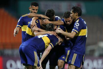 Los jugadores de Boca abrazan a Eduardo Salvio, que acaba de anotar un gol que vale tres puntos: el equipo xeneize venció 1-0 al DIM en Medellín (Colombia).