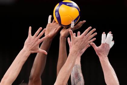 Los jugadores de Polonia e Italia alcanzan el balón durante el partido del grupo A de la ronda preliminar de voleibol masculino entre Polonia e Italia en los Juegos Olímpicos de Verano de 2020, el lunes 26 de julio de 2021, en Tokio, Japón.