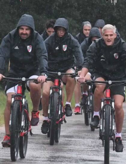 Los jugadores de River Plate en bicicleta bajo la lluvia
