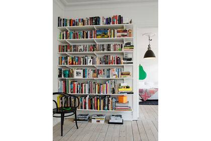 Los libros pueden ser el toque de color en un ambiente de base clara. En este caso, una gran estantería blanca se mimetiza con el muro y toma los colores de los objetos que contiene