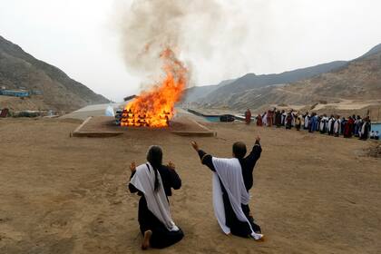 Los líderes de la iglesia evangélica cristiana Misión israelita del Nuevo Pacto Universal se arrodillan durante un ritual de quema de carne de animales
