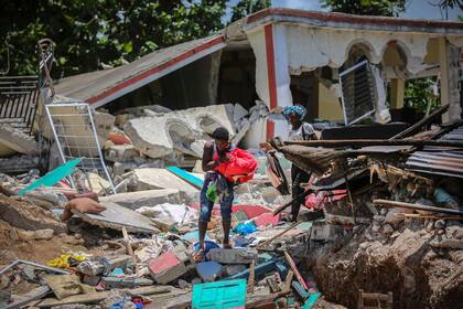 Los lugareños buscan recuperar sus pertenencias donde antes se erguían sus casas ahora destruidas por el terremoto, en Haití