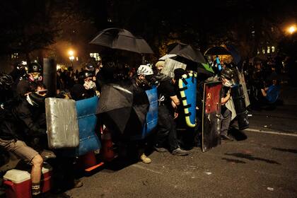Los manifestantes forman una barricada con paraguas, flotadores, trineos y almohadillas de fútbol americano