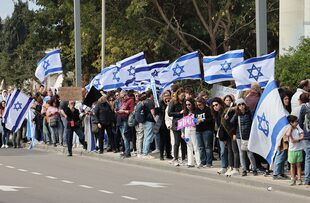 Los manifestantes israelíes levantan banderas y pancartas nacionales mientras se manifiestan en Tel Aviv el 13 de febrero de 2023, contra las controvertidas reformas legales que promociona el gobierno de extrema derecha del país. (Foto de JACK GUEZ / AFP)