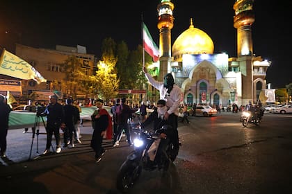Los manifestantes ondean la bandera de Irán mientras se reúnen en la Plaza Palestina en Teherán el 14 de abril de 2024