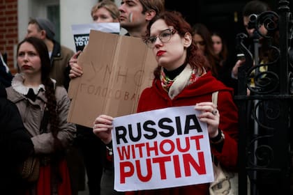 Los manifestantes sostienen pancartas mientras se reúnen frente a la embajada rusa, en Londres, el 17 de marzo de 2024 para protestar contra las elecciones presidenciales de Rusia.