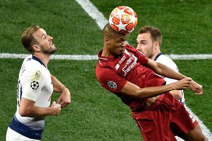 El centrocampista brasileño del Liverpool, Fabinho, cabecea el balón entre dos jugadores contrarios
