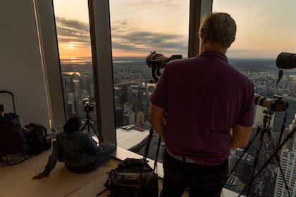 Los miembros de la Asociación de Astrónomos Aficionados de Nueva York observan cómo el sol sale parcialmente eclipsado un rascacielos en la ciudad de Nueva York.