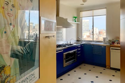 Los muebles de cocina destacan en azul y contrastan con la pared mostaza. La vista abierta a Plaza San Martín es la estrella de este ambiente.