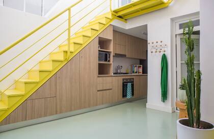 Los muebles de la cocina continúan con un espacio de guardado bajo la escalera. Sobre la mesada, las obras de David Sisso suman color.