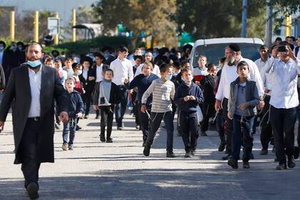 Los niños de la comunidad judía ultraortodoxa israelí caminan frente a una escuela judía talmúdica, que estaba abierta en violación de las reglas de confinamiento, luego de su cierre por las fuerzas de seguridad israelíes, en la ciudad de Ashdod el 22 de enero de 2021