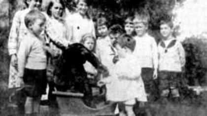 Los niños de Uley se divierten llevando a John Daniel por la aldea en una carretilla