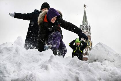 Los niños juegan en lo alto de una colina nevada en la Plaza Roja frente a la torre Spasskaya del Kremlin después de una fuerte nevada en Moscú, el 4 de diciembre de 2023.