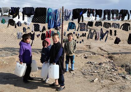 Los niños se aferran a los contenedores de agua en el campamento de al-Hol