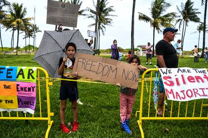 Los niños sostienen pancartas mientras participan en una protesta de "Freedom Rally" en apoyo de la apertura de Florida en South Beach en Miami, el 10 de mayo de 2020