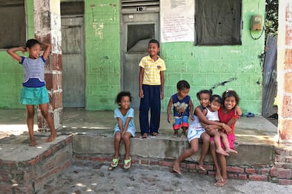 Los niños van a la escuela en la cercana Sevilla; cruzan el río con los brazos en alto para que no se les mojen los útiles