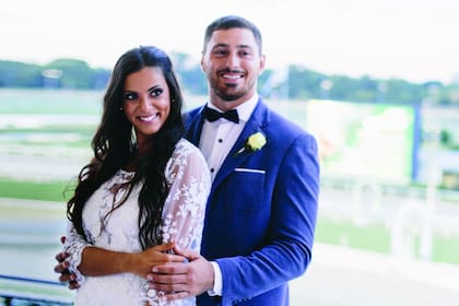 Los novios en las tribunas de Palermo. “Belu” eligió un diseño de Natalia Antolín, mientras que su marido llevó moño y una flor en el ojal.