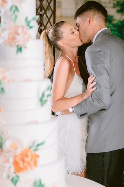 Los novios y un beso apasionado antes de cortar la torta de cinco pisos. Para ese momento, Chiara cambió su vestido por uno corto con falda de plumas de Atelier Emé, mientras que Joaquín se puso un saco más informal.