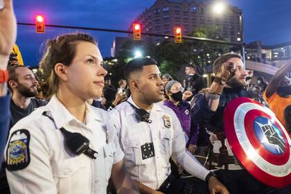 Los oficiales del Departamento de Policía de Columbus se arrodillan y se unen a recitar The Lords Prayer con los manifestantes mientras marchan por North High Street, Ohio