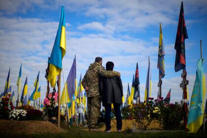 Los padres del soldado ucraniano Ruslan Zhumaboev, recientemente asesinado, permanecen junto a su tumba en un cementerio durante el Día de los Defensores de Ucrania en Kharkiv, Ucrania, el viernes 14 de octubre de 2022.