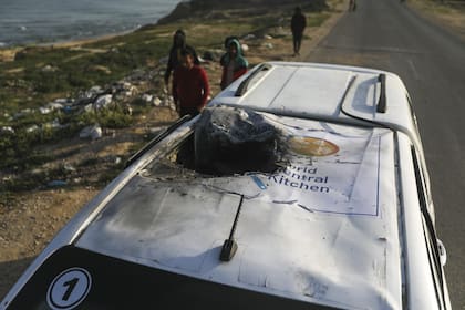 Los palestinos inspeccionan un vehículo con el logo de World Central Kitchen destrozado por un ataque aéreo israelí en Deir al Balah, Franja de Gaza, el martes 2 de abril de 2024.