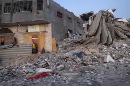Los palestinos se sientan junto a un edificio dañado rodeado de escombros en el campamento de al-Bureij en el centro de la Franja de Gaza el 2 de junio de 2024, en medio del conflicto en curso entre Israel y el grupo militante palestino Hamas.