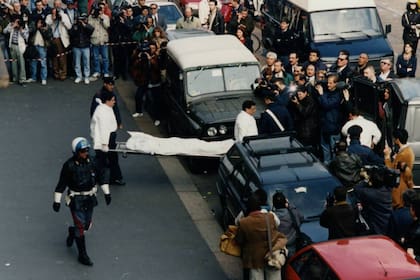 Los paramédicos trasladan el cuerpo sin vida de Maurizio Gucci, ante la mirada de infinidad de fotógrafos y curiosos, en la via Palestra