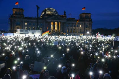 Los participantes encienden sus teléfonos móviles durante una manifestación contra el racismo y la política de extrema derecha frente al edificio del Reichstag en Berlín (CHRISTIAN MANG / AFP)�