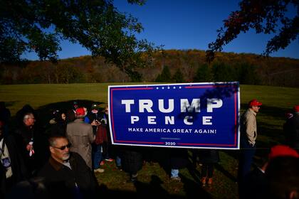 Los partidarios de Donald Trump sostienen un cartel antes de que se celebre un mitin el 31 de octubre de 2020 en Newtown, Pensilvania
