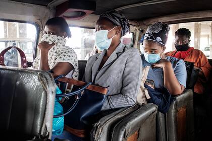 Los pasajeros con mascarilla se sientan en un minibús mientras esperan al conductor en la parada de taxis de Bara en Soweto, Johannesburgo, el 17 de diciembre de 2020