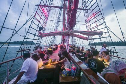 Los pasajeros disfrutan de una cena en el Royal Albatross, un velero de lujo que ofrece experiencias de navegación junto a las mascotas
