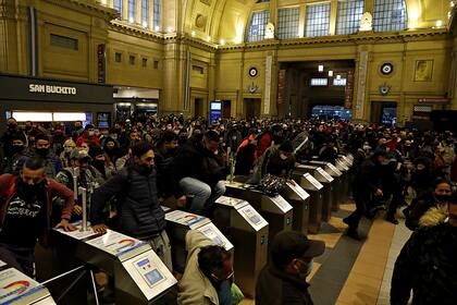 Los pasajeros saltan los molinetes para llegar a las formaciones luego de un día de caos en Constitución