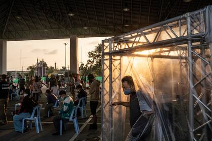 Los pasajeros son rociados con un desinfectante en una carpa de descontaminación en un punto de control en Chatchai, Tailandia el 31 de marzo de 2020