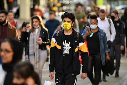 Los peatones, algunos con tapabocas debido a la pandemia de coronavirus, caminan en Manchester, noroeste de Inglaterra el 3 de agosto de 2020