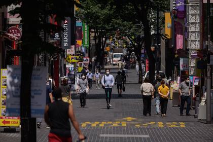 Los peatones con tapabocas como medida de protección contra el coronavirus caminan por el distrito comercial de Myeongdong en Seúl el 25 de agosto de 2020