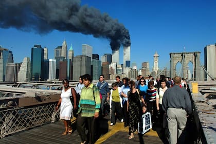 Los peatones cruzan el Puente de Brooklyn alejándose de las torres de World Trade en llamas antes de su derrumbe