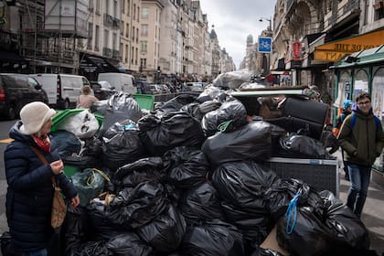 Los peatones pasan junto a los residuos que se han ido acumulando en la acera mientras los recolectores de residuos están en huelga desde el 6 de marzo contra la propuesta de reforma de las pensiones del gobierno francés, en París el 13 de marzo de 2023.