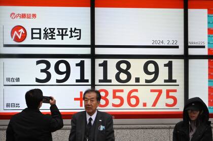 Los peatones pasan junto a un tablero electrónico que muestra el índice Nikkei de la Bolsa de Tokio por encima de 39.000 puntos en una calle de Tokio