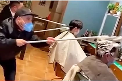 Los peluqueros trabajan con sus elementos adheridos a palos de más de un metro de largo