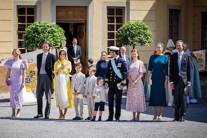 Los príncipes Carlos Felipe y Sofía con sus cuatro hijos posan con los cinco padrinos del bautismo: a la izquierda, Tiara Larsson (es ahijada de la princesa Sofía), Frederik von der Esch (es ahijado de la reina Silvia y amigo de Carlos Felipe), la princesa Estella (13; la hija mayor de Victoria, con un vestido floreado), Sandrine Roussel (a la derecha y vestida de azul, la medio hermana de Athina Onassis) y su marido, Claes Kockum (es amigo del príncipe Carlos Felipe; se conocieron en el internado de Lundsberg). Detrás de ellos, a la izquierda y a la derecha, se aprecia el monograma de Inés, que tiene una gran “I” rematada con una corona, ambas formadas por flores de diferentes colores.