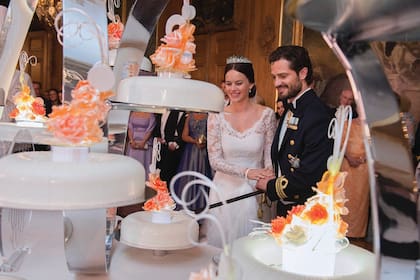 Los príncipes cortan con un sable una de las doce tortas de boda, colocadas en un original soporte metálico que recordaba a una carroza