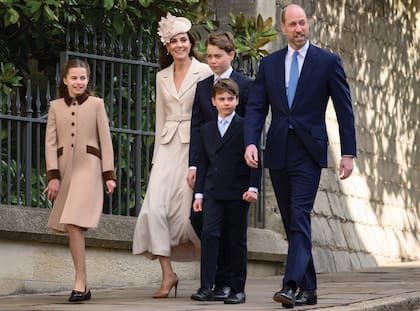 Los príncipes de Gales y sus hijos, George, Charlotte y Louis. Kate impactó con un conjunto de dos piezas de Self-Portrait que combinó con un sombrero de Sean Barrett con flores. Y Charlotte, por su parte, volvió a optar por el tapado beige con detalles en velvet marrón que lució en Navidad. Los hombres de la familia vistieron traje oscuro y corbata celeste