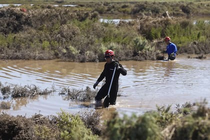 Los rastrillajes se hacen en kayaks y a pie, paso a paso, por las lagunas que se formaron en el ingreso a la localidad de Cerri tras el temporal