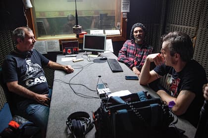 En un híbrido de ficción y realidad, Popa Arnedo, a la izquierda, conduce una de las entrevistas de la película –en el estudio de una FM barrial– con Pablo Guerra, de Caballeros de la Quema, y Lucas Rocca, ex La Franela, actualmente en Los Maniquíes.