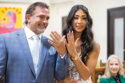 Los recién casados exhiben sus anillos, que tienen grabados sus nombres y la fecha de la boda.